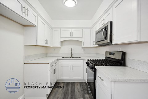 a white kitchen with white cabinets and a black stove
